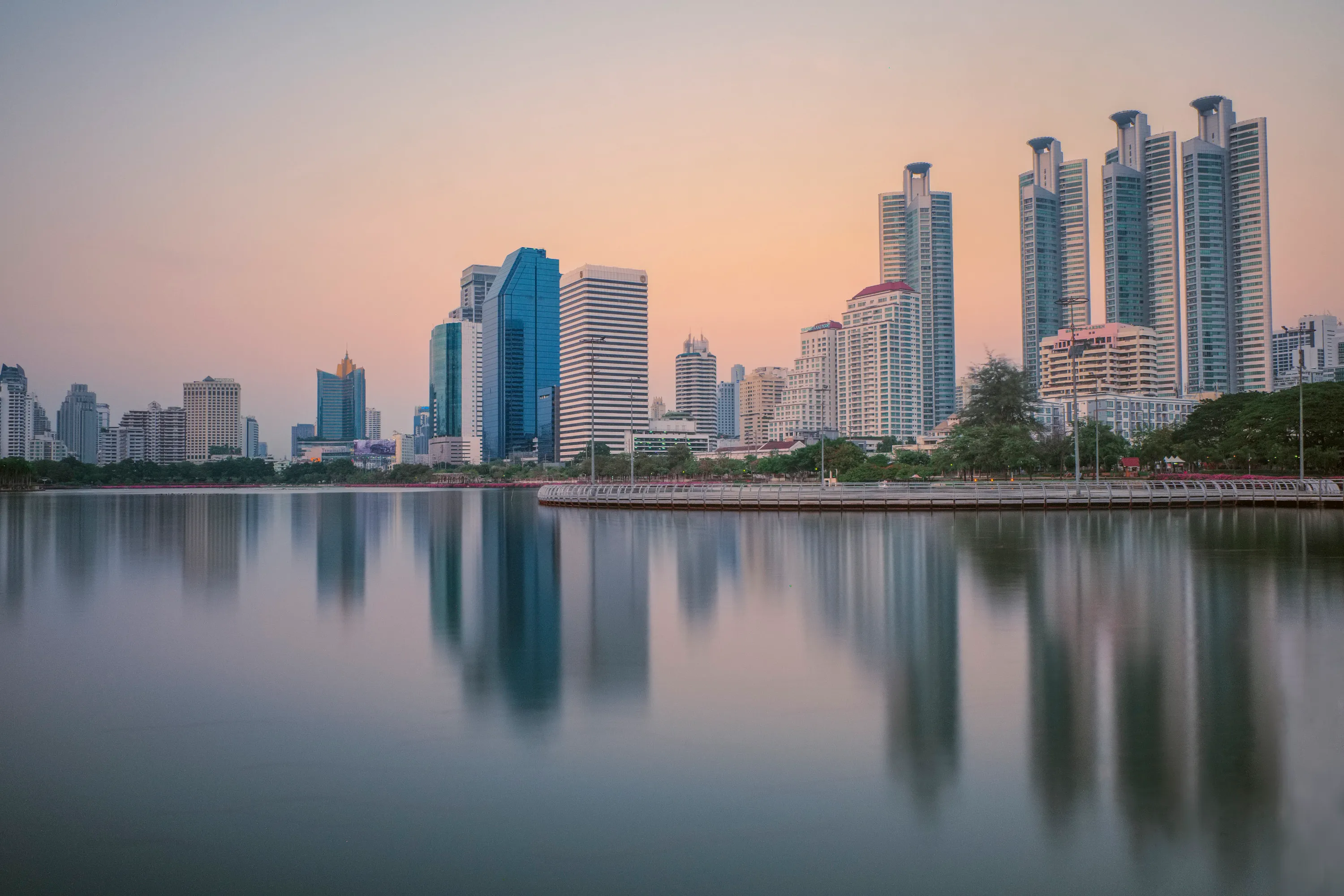 Une photo à exposition longue des grattes ciel qui reflètent sur l'eau dans le parc Benchakitti à Bangkok.