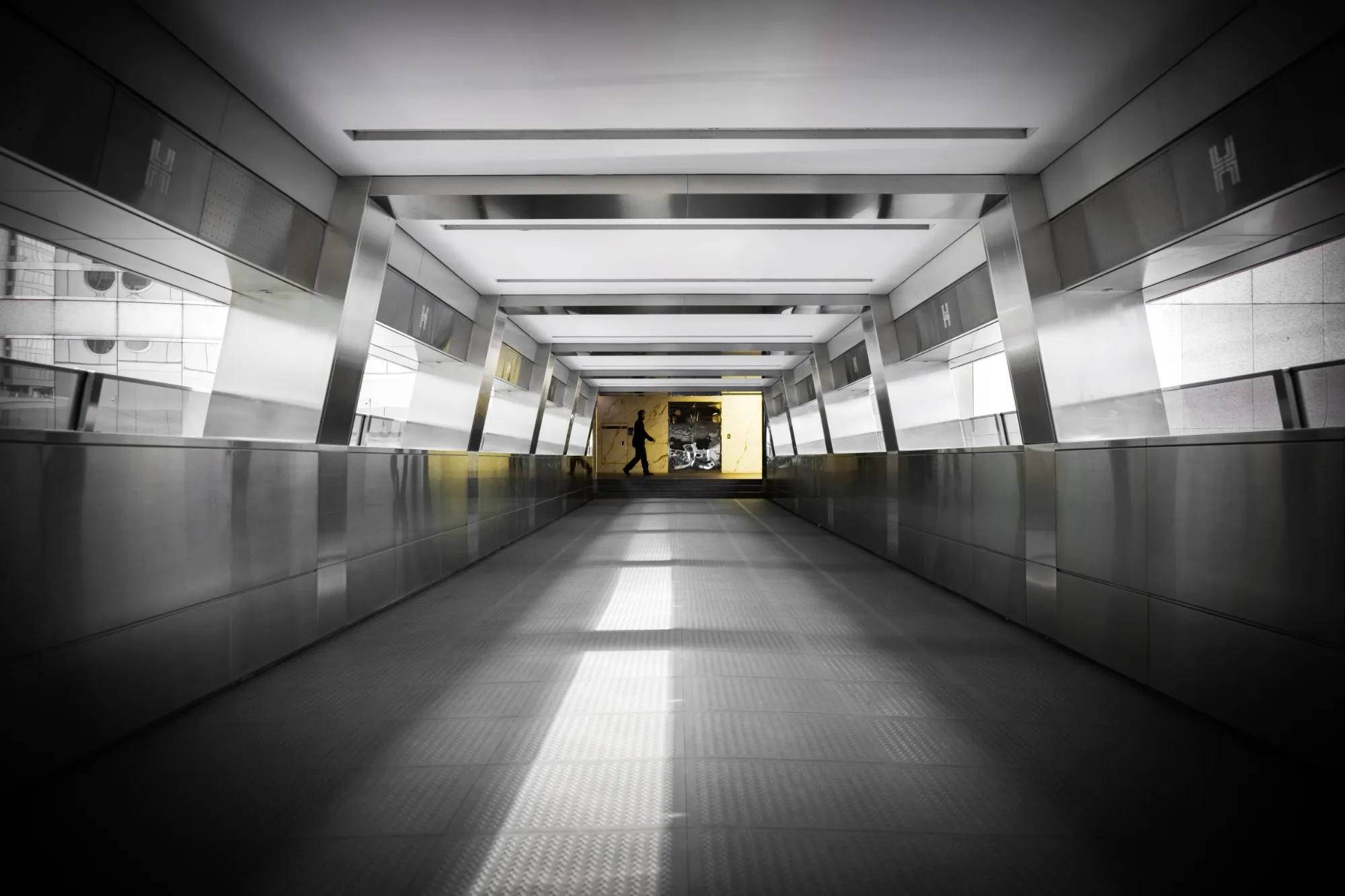 la silhouette d'un passant au fond d'un couloir moderne