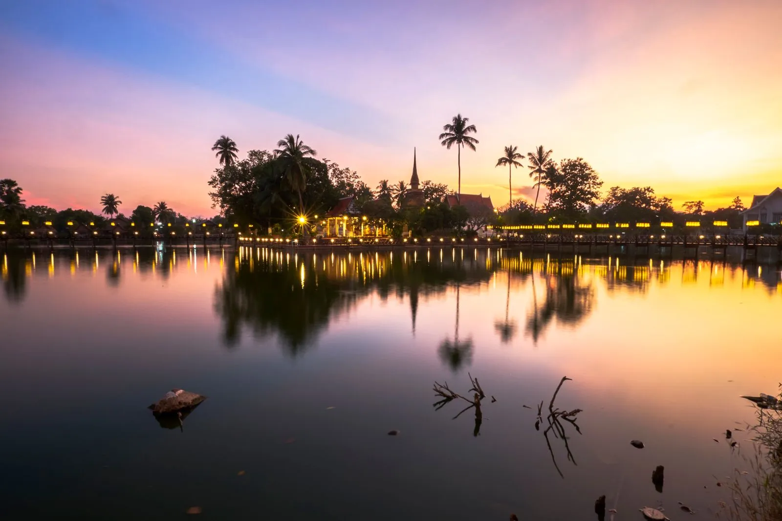 Une temple bouddhiste qui se reflète sur un petit lac durant un couché de soleil à Sukhothai , en thaïlande 