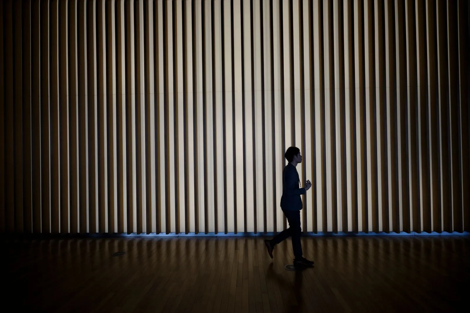 la silhouette d'un passant devant un mur illuminé